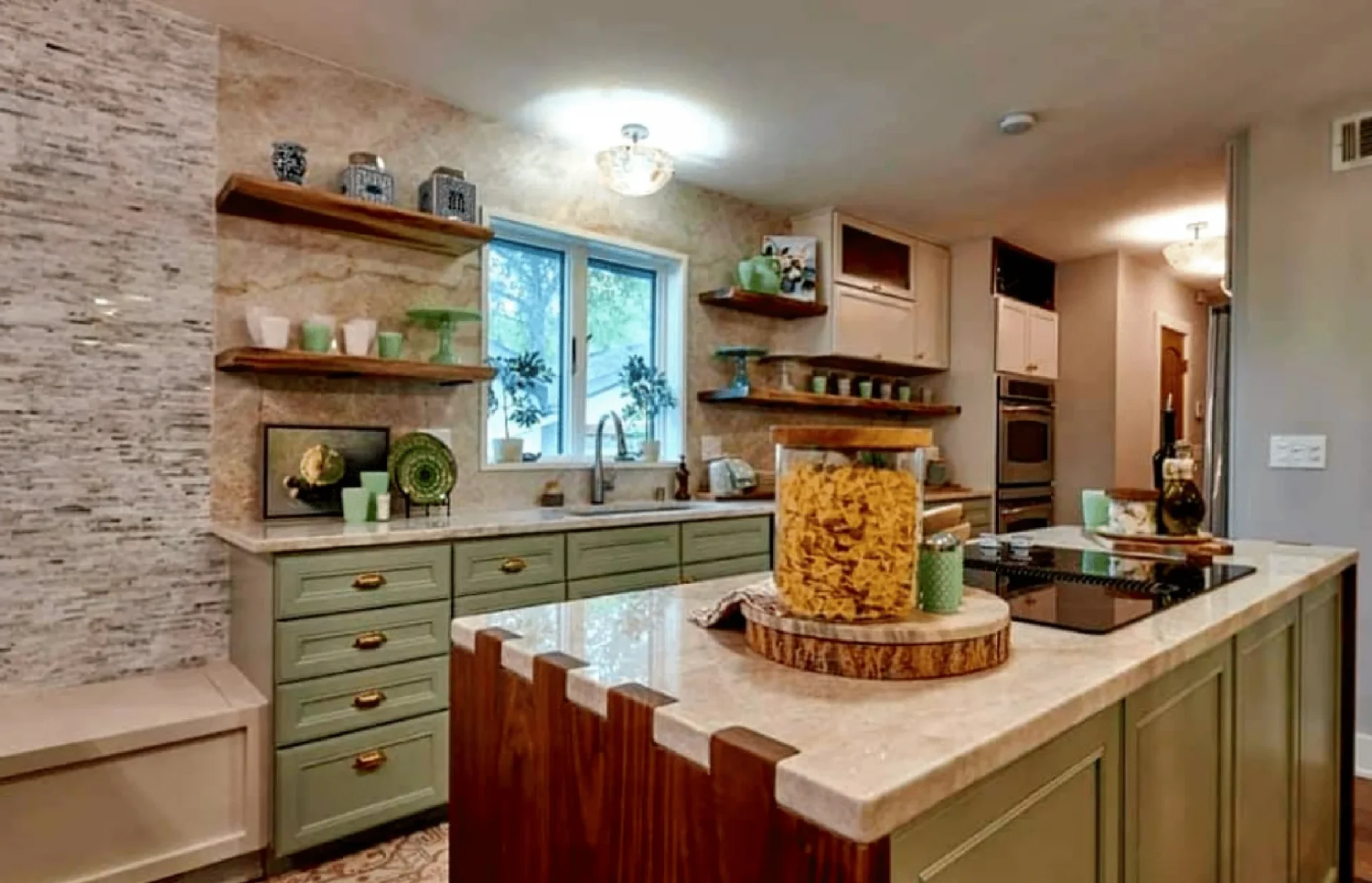 A modern kitchen interior with olive green cabinets, quartz countertops, and a large window letting in natural light.