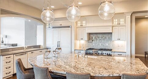 Modern kitchen with granite countertops from a top countertop company, white cabinetry, and pendant lights over a central island.