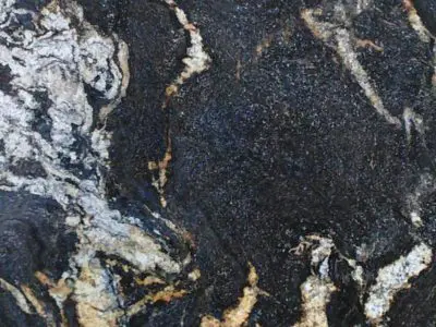 Close-up view of a natural stone surface with intricate white and golden vein patterns on a dark background.