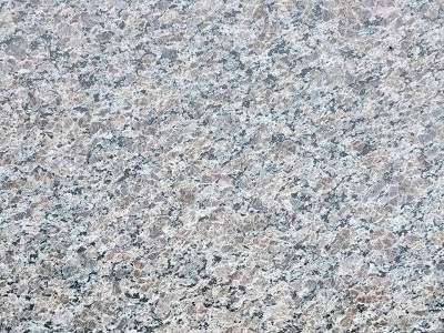 Close-up of a speckled gray granite surface, suitable for natural stone countertop installation, with varied texturing and coloration.