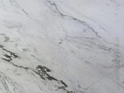 Close-up of a natural stone marble surface with intricate gray veins on a white background.