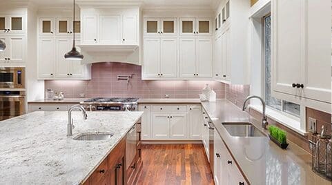 Elegant kitchen with white cabinetry, provided by a top countertop company, and hardwood floors, featuring a central island and modern appliances.