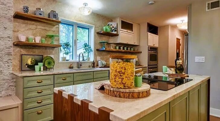 Modern kitchen with green cabinets, granite countertops from a reputable countertop company, and a view of a garden through a window.