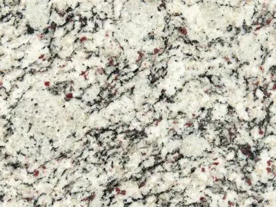 Close-up of a natural stone surface with a speckled pattern of gray, white, and black with hints of red.