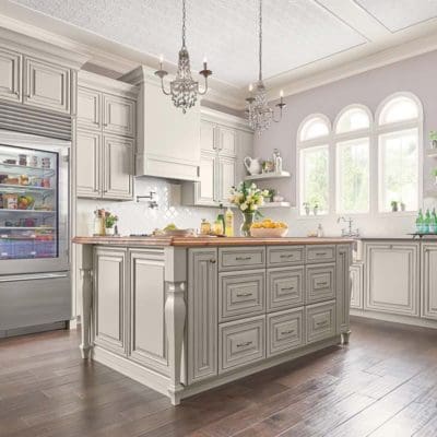 Elegant kitchen interior with a central island, custom countertops, grey cabinetry, hardwood floors, and arched windows.