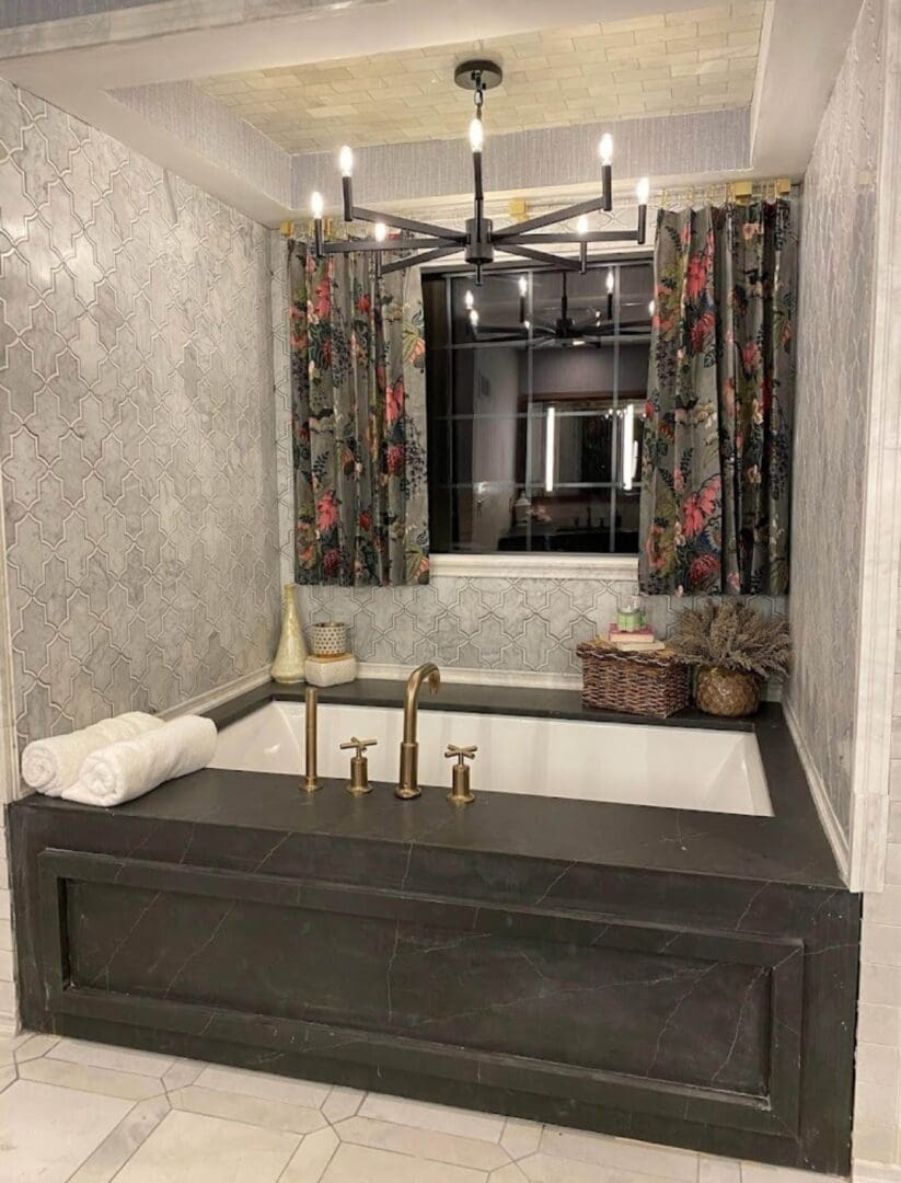 A stylish bathroom featuring a large built-in bathtub, geometric tiles, floral curtains, and modern flooring projects.