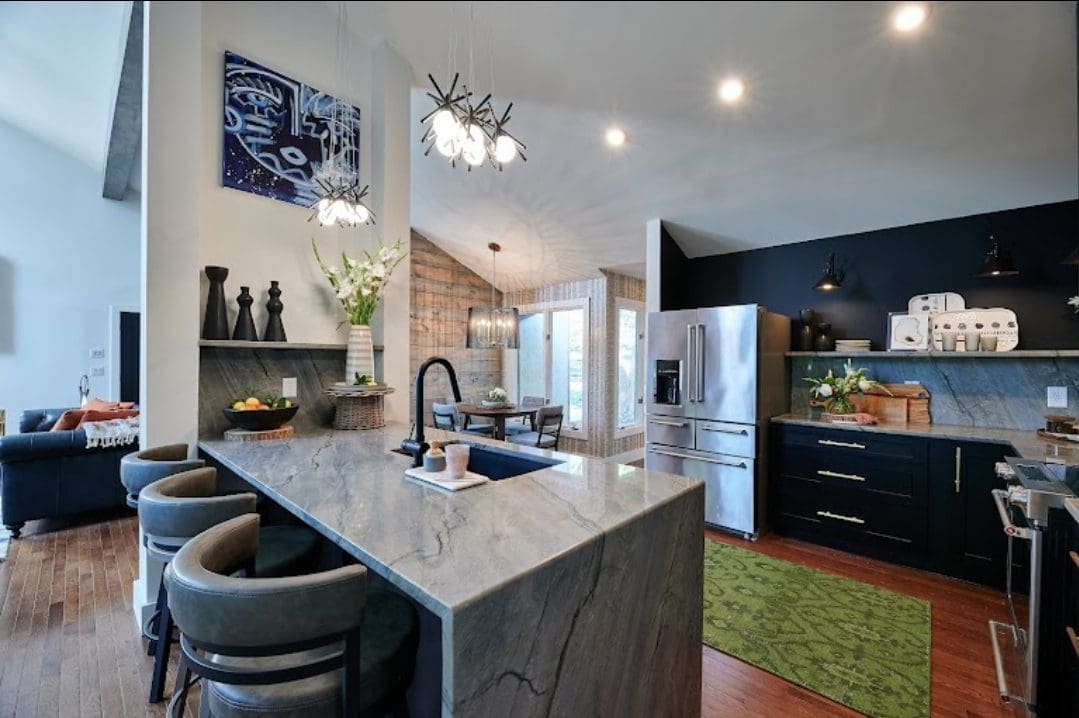 Modern kitchen interior with a marble island, stainless steel appliances, dark cabinets, pendant lighting, and flooring projects.