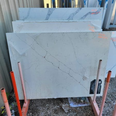 Marble countertop remnants with visible veins leaning against a wall, surrounded by construction materials.