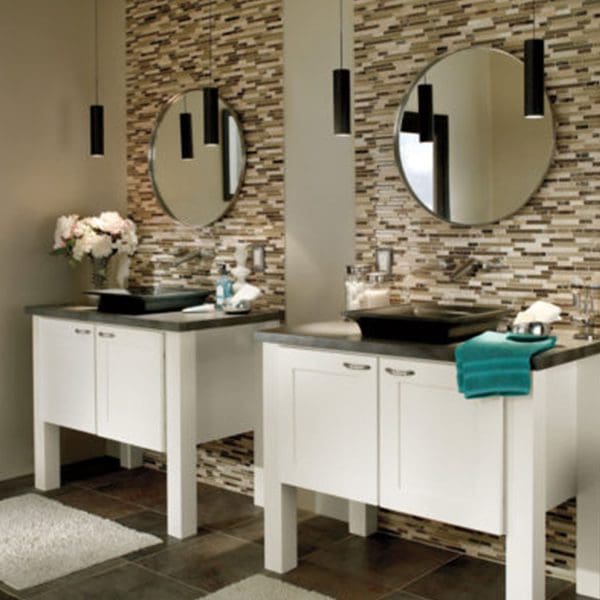 A modern bathroom with two white vanities, custom countertops, round mirrors, and a mosaic tile backsplash.