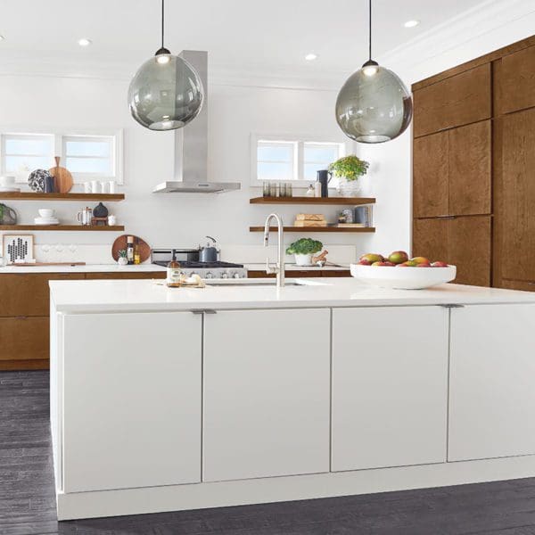 Modern kitchen interior with white cabinets, custom countertops, wooden accents, and hanging glass pendant lights.