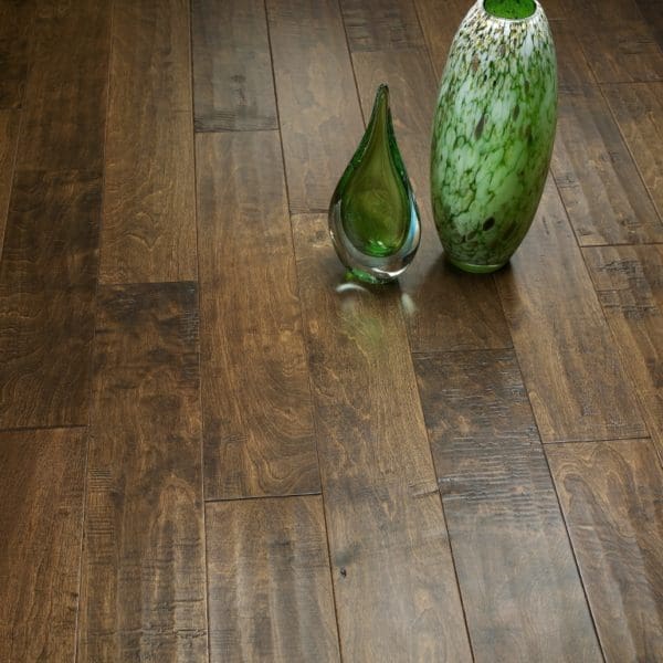 Two decorative vases on a dark carpet floor, one clear glass and one green with a white pattern.