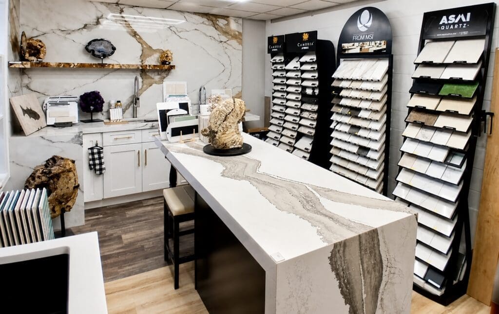 Anytopshop showroom with quartz waterfall island, stone slab display, and wall-mounted countertop samples.