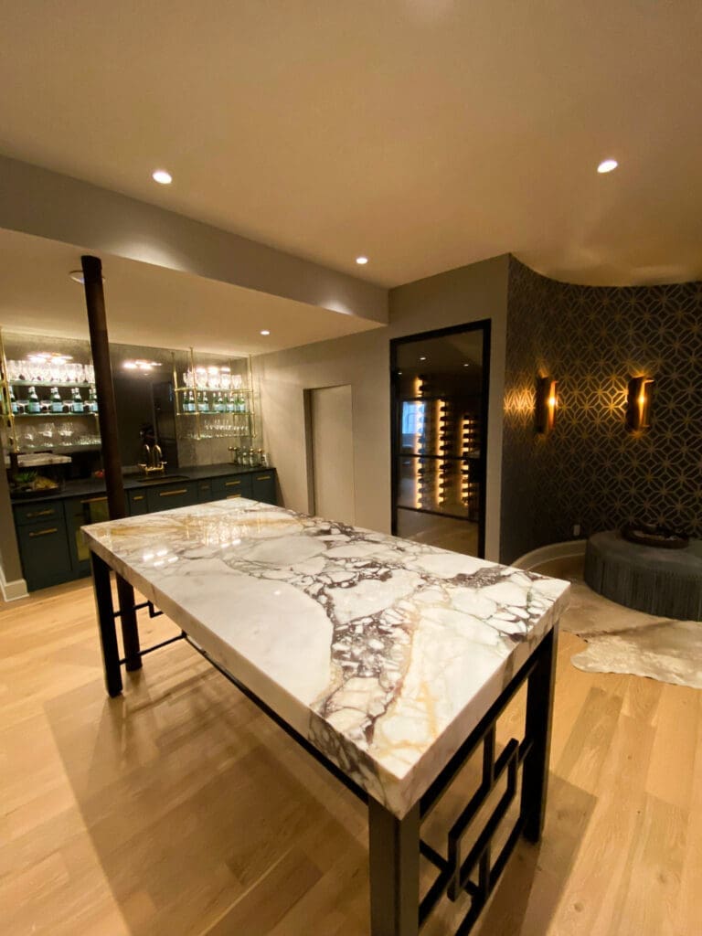 Luxury marble tabletop featuring dramatic gray veining in a sophisticated entertainment space with custom cabinetry, wine storage, and contemporary lighting.