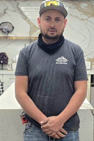 Charly, a professional countertop installer from Any Top Shop, standing in a custom kitchen with luxury stone surfaces and modern cabinetry