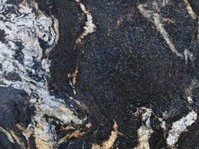 Close-up view of a natural stone surface with intricate white and golden vein patterns on a dark background.