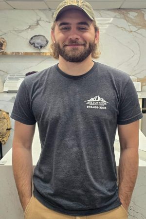 Jason, office assistant at Any Top Shop, standing in a showroom kitchen with custom stone countertops and modern cabinetry