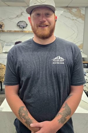 Quinten, professional countertop installer at Any Top Shop, standing in a showroom with custom stone surfaces and kitchen displays
