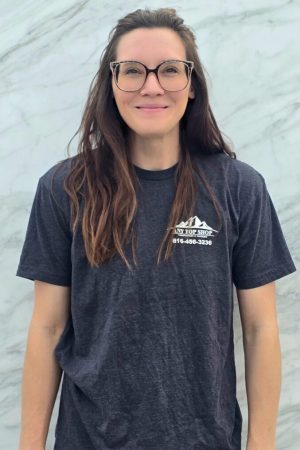 Hope, Design and Sales Manager at Any Top Shop, standing in front of a natural stone slab used for custom countertop projects