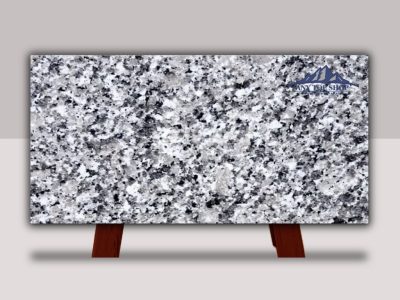 Granite slab with a speckled pattern displayed upright on wooden stands.
