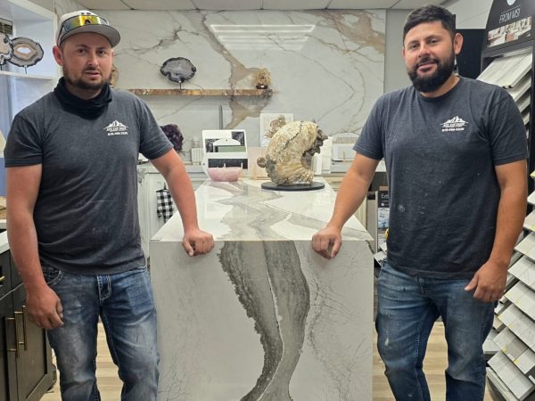 Charly and Victor from the Any Top Shop installation team standing beside a custom stone island in the showroom