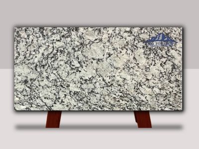 Polished granite slab with gray, black, and white speckles on a wooden stand.