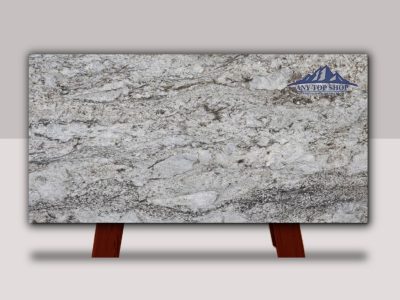 Granite countertop slab with gray and white tones, displayed on wooden stands.