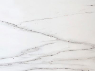 Close-up of Calacatta Lincoln marble showcasing a white background with soft gray veining and natural stone detail.