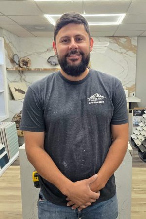 Victor, lead installer at Any Top Shop, standing in the showroom near premium stone slabs and countertop materials