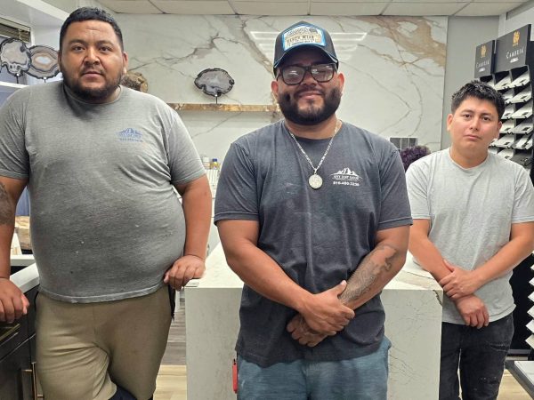 Dave, Oliver, and Ferdin of the AnyTopShop fabrication team standing in the countertop showroom surrounded by premium stone slab samples and custom countertop displays in the Kansas City metro area.