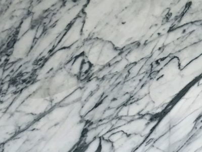 Close-up of Statuarietto marble featuring bold gray veining, dramatic movement, and natural variation across a white marble surface.